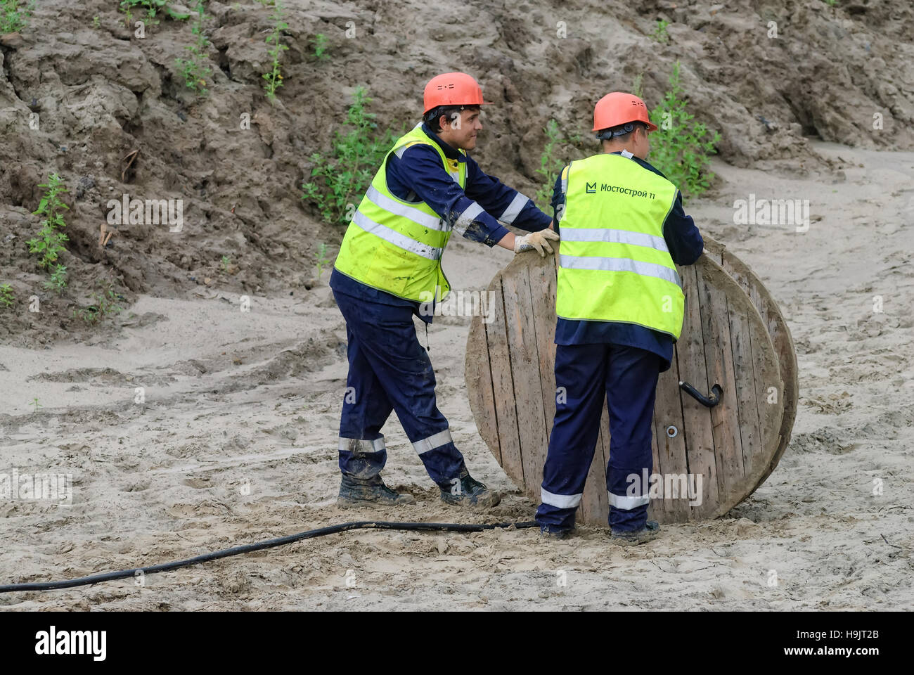 Due lavoratori rullo di trazione cavo ad alta tensione di linea Foto Stock