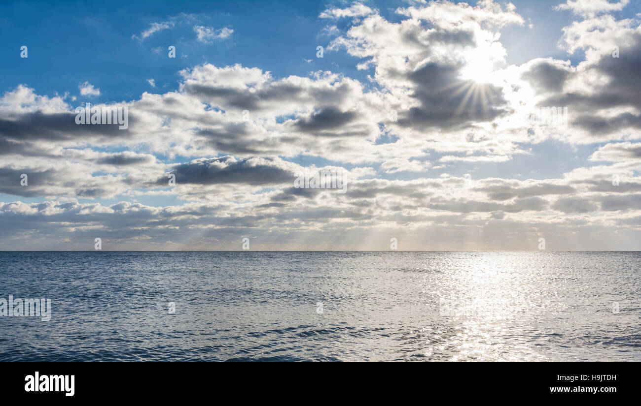 Sun dietro le nuvole sopra il mare. Foto Stock