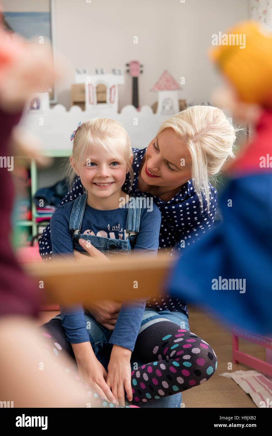 Felice bambina guarda Punch e Judy mostrano insieme con la madre nella stanza dei bambini Foto Stock