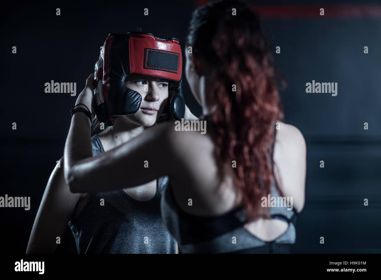 Donna aiutando boxer femmina mettendo in guardia di testa Foto Stock