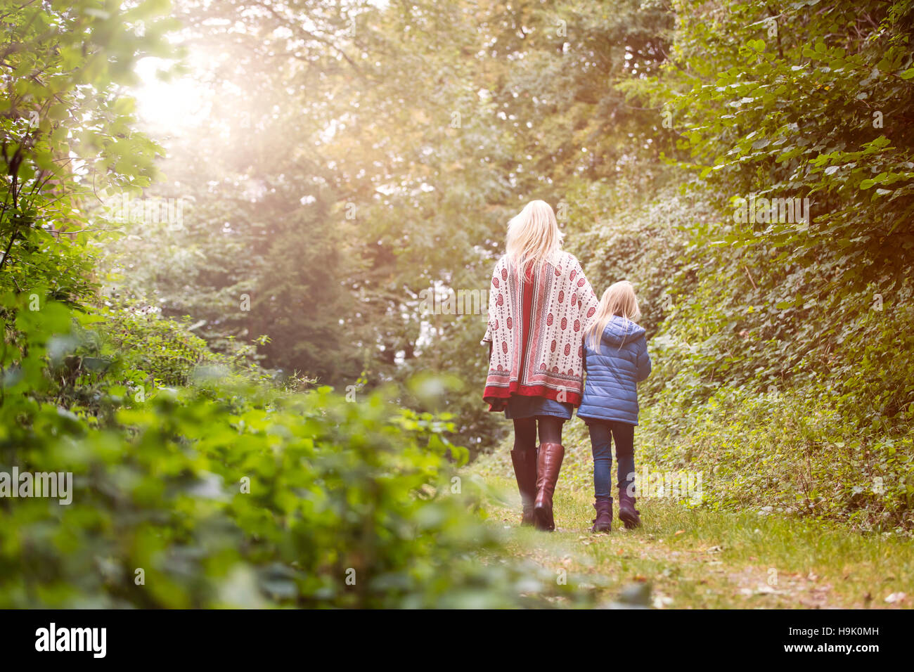 Vista posteriore della madre e figlia piccola a piedi nella foresta autunnale Foto Stock