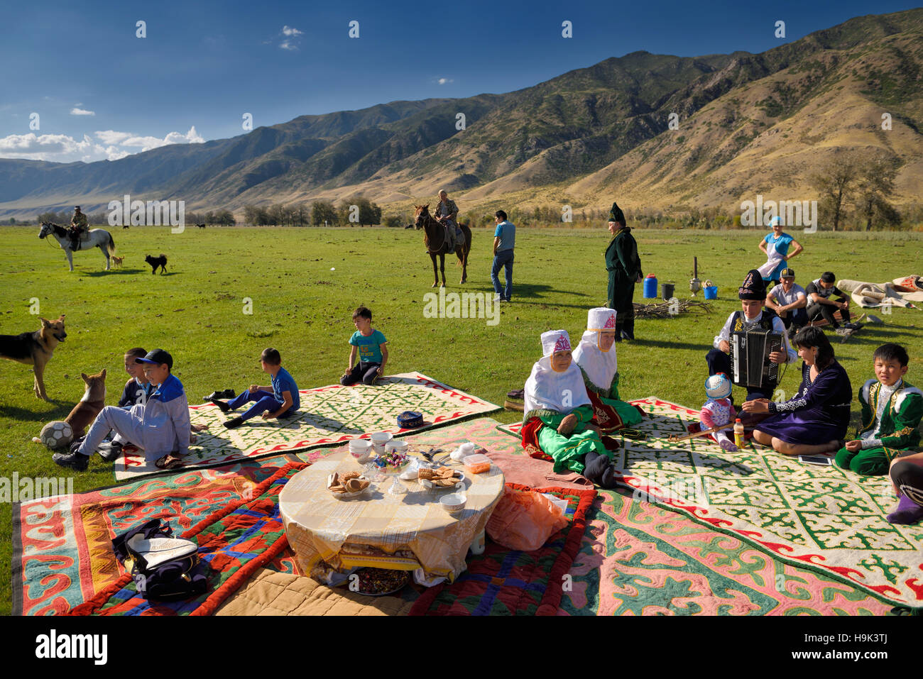Soggiornare concittadini riuniti per un picnic in pascolo dal fiume Chilik e Kungey Alatau montagne Kazakistan Foto Stock