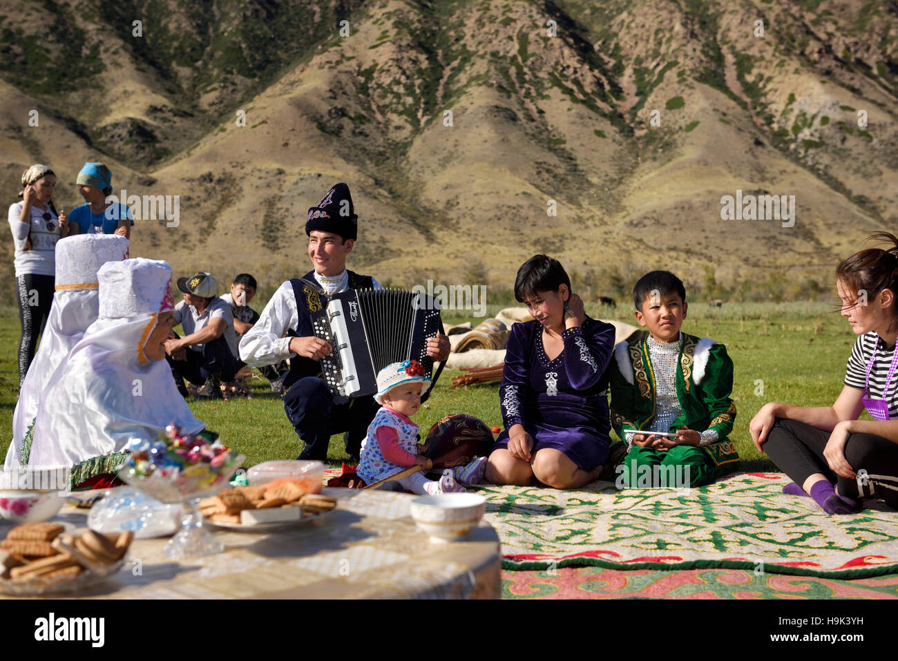 Soggiornare alcuni concittadini in abiti tradizionali a un picnic dal fiume Chilik Kungey Alatau montagne Kazakistan Foto Stock