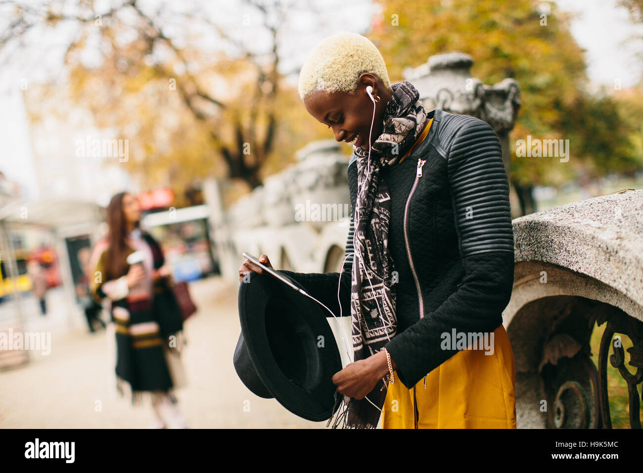 Moderno e giovane africano donna americana in posa con caffè di andare e il telefono cellulare all'aperto Foto Stock