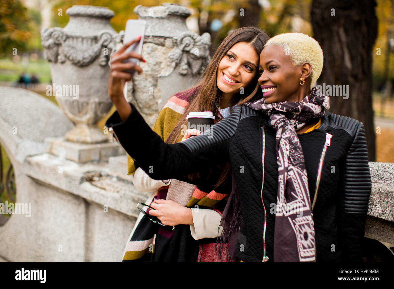 Giovane americano africano e caucasico donne tenendo selfie outdoor Foto Stock