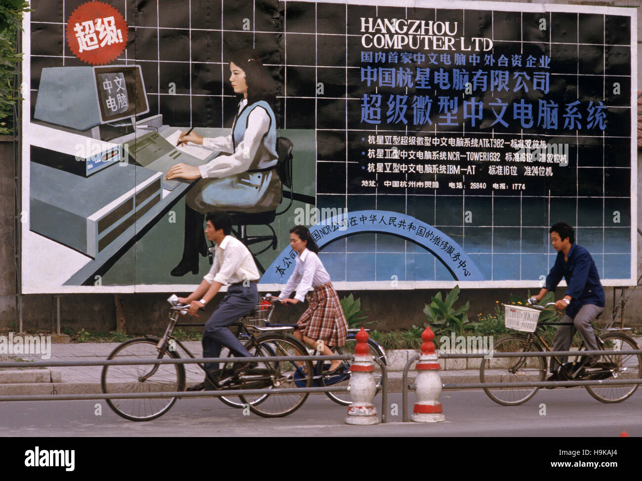 I ciclisti in sella a fronte di Hangzhou Computer società poster, Hangzhou, nella provincia di Zhejiang, Cina Foto Stock