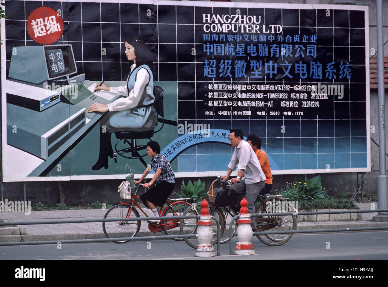 I ciclisti in sella a fronte di Hangzhou Computer società poster, Hangzhou, nella provincia di Zhejiang, Cina Foto Stock