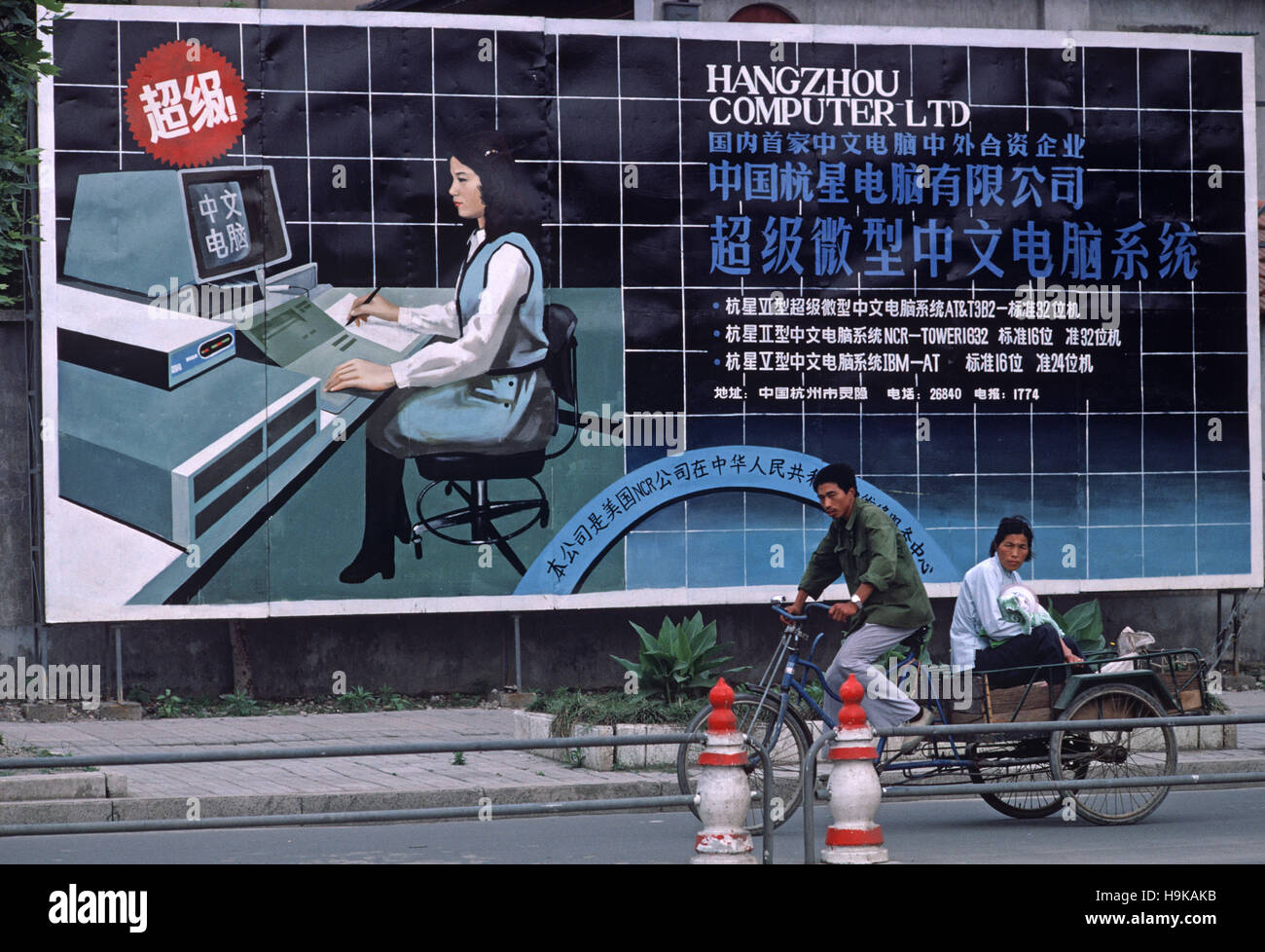 I ciclisti in sella a fronte di Hangzhou Computer società poster, Hangzhou, nella provincia di Zhejiang, Cina Foto Stock
