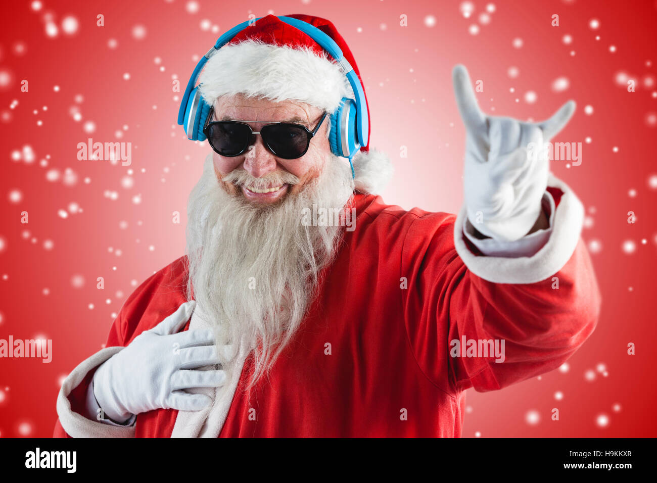 Immagine composita di santa claus che mostra segno avvisatore acustico durante l'ascolto di musica con le cuffie Foto Stock