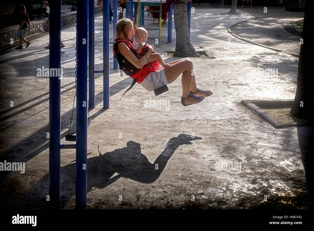 Oscillazione del bambino della madre. La giovane madre e il suo bambino che gioca sul parco di ricreazione altalene. Thailandia, S. E. Asia Foto Stock
