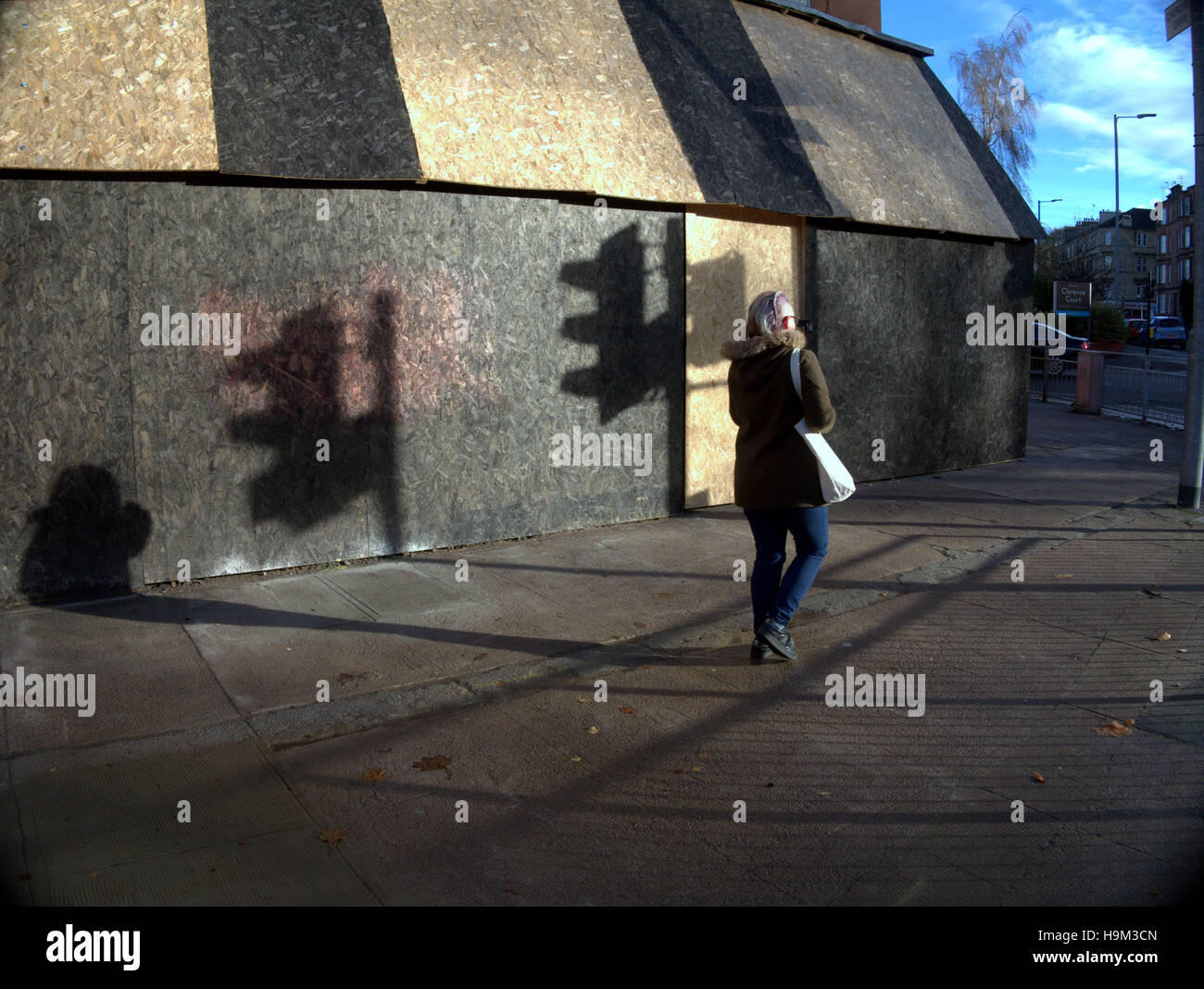 Basso sole invernale su Urban singola persona camminare da solo le ombre del semaforo Foto Stock