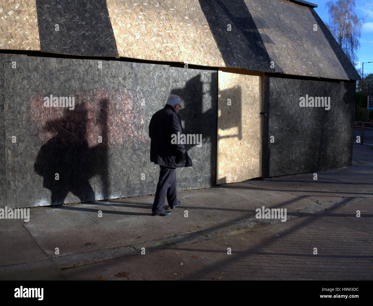 Basso sole invernale su Urban singola persona camminare da solo le ombre del semaforo Foto Stock