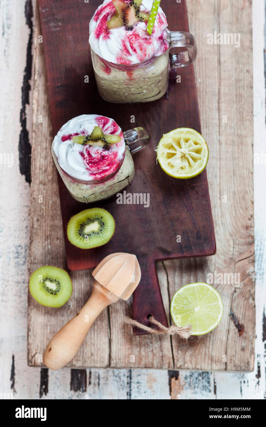 Due bicchieri di kiwi limes smoothie con crema di noce di cocco e salsa di lamponi Foto Stock