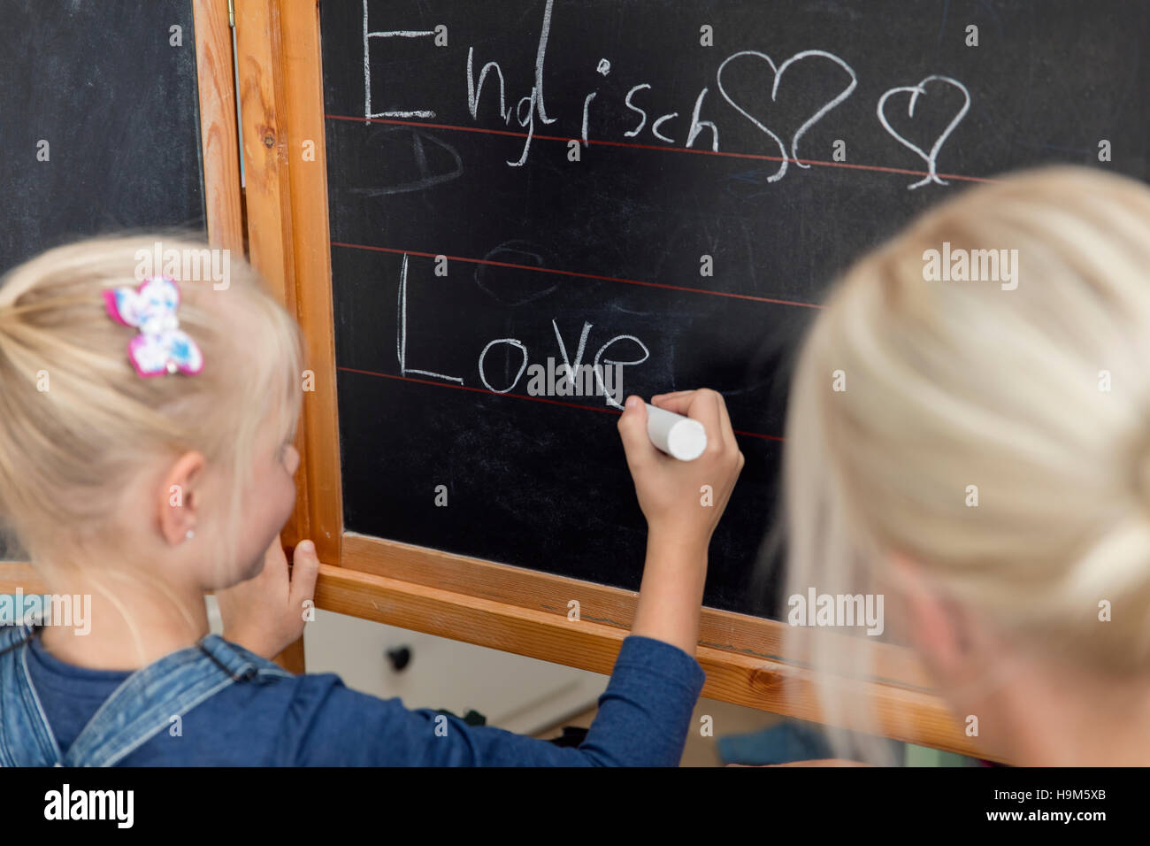 Madre guarda la sua figlia a scrivere la parola "amore" sulla lavagna Foto Stock