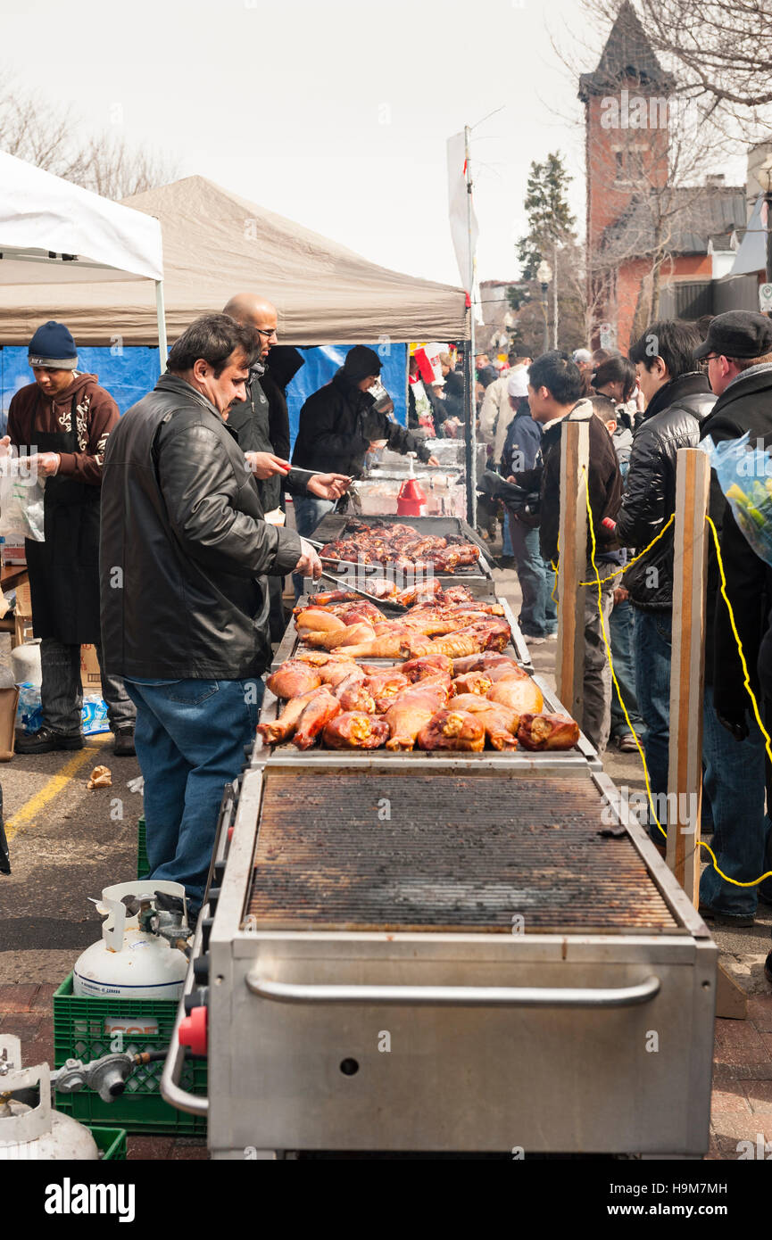 Venditrice di cibo di strada grigliando e vendendo zampe di tacchino grigliate all'esterno durante un evento della comunità, il Canada Foto Stock