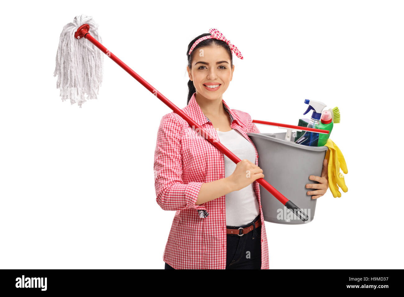 Felice giovane donna in possesso di una scopa e un secchio pieno di prodotti di pulizia isolati su sfondo bianco Foto Stock