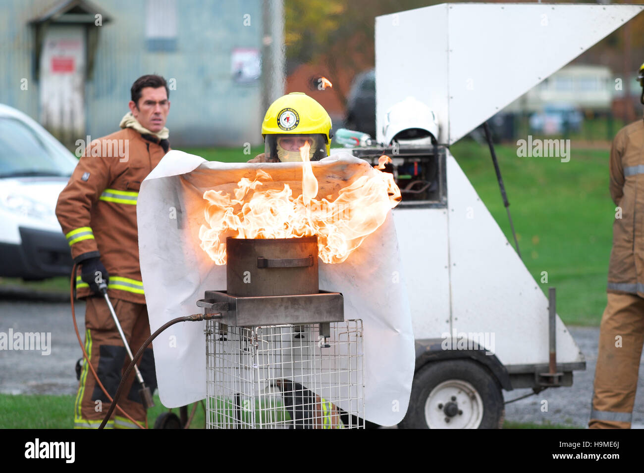 La salute e la sicurezza sul sito di formazione antincendio utilizzando una coperta antincendio per estinguere una padella di olio sotto la guida REGNO UNITO Foto Stock