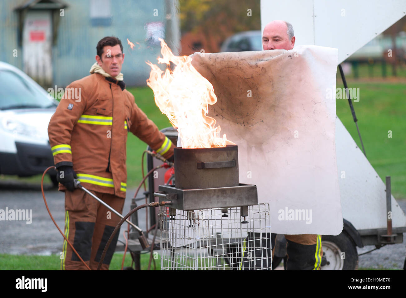 La salute e la sicurezza sul sito di formazione antincendio utilizzando una coperta antincendio per estinguere una padella di olio sotto la guida REGNO UNITO Foto Stock