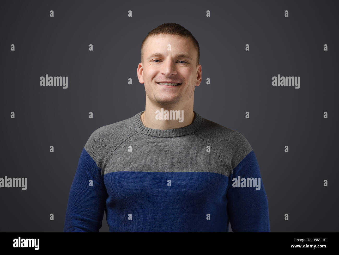 Ritratto di un giovane uomo gay che sorride. Foto emotivo in studio su sfondo nero Foto Stock