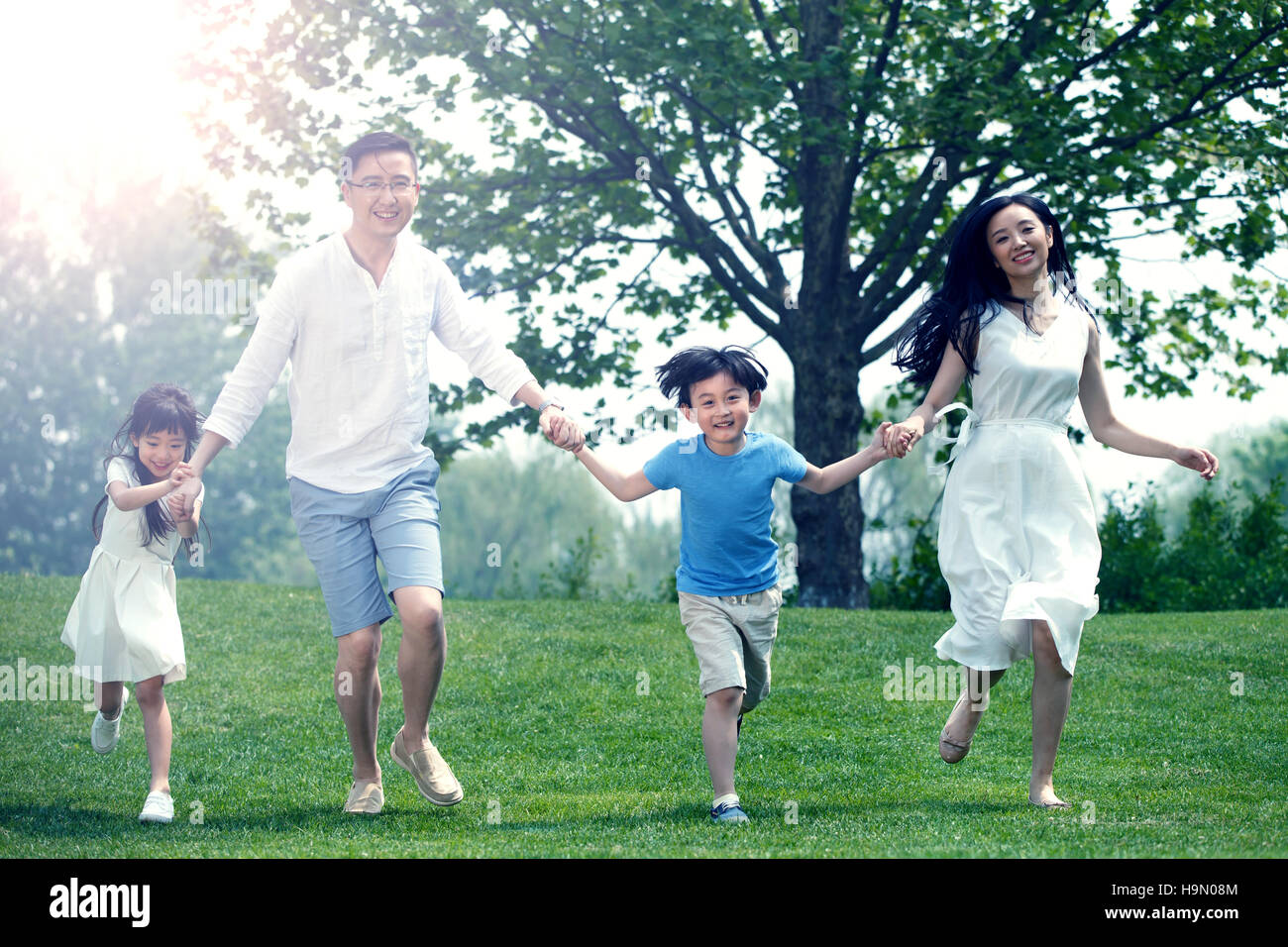 Famiglie felici eseguire sull'erba Foto Stock