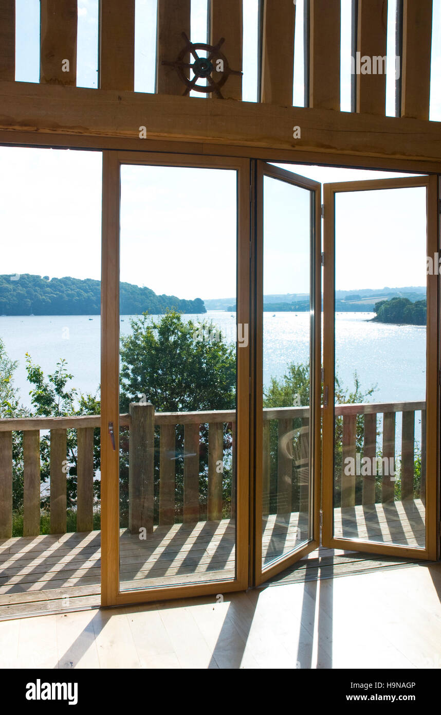 La piegatura delle porte in vetro che si affaccia su ponte di legno con balcone. Foto Stock