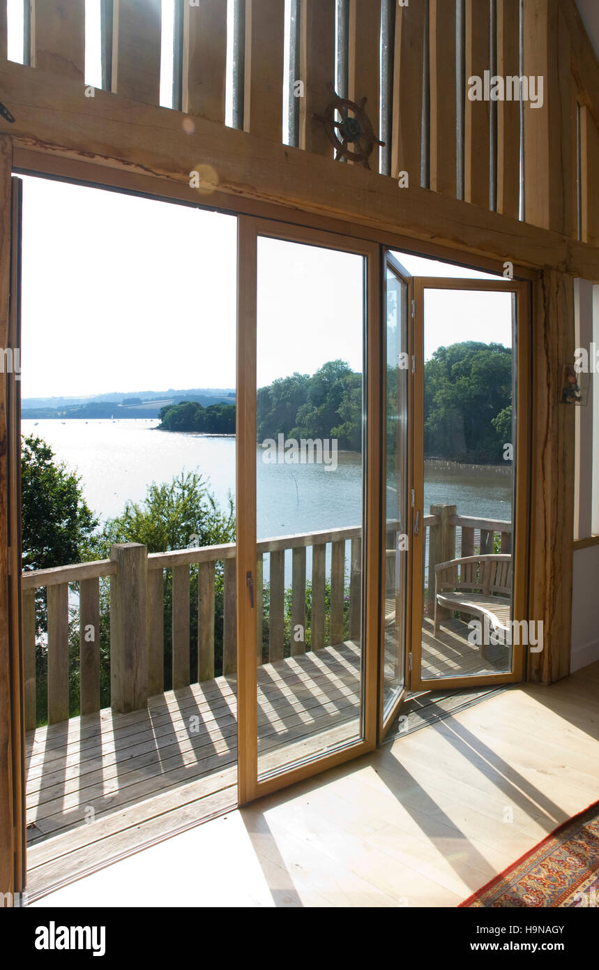 Porte a vetro su legno balcone, vista su estuario, alla luce del sole. Foto Stock