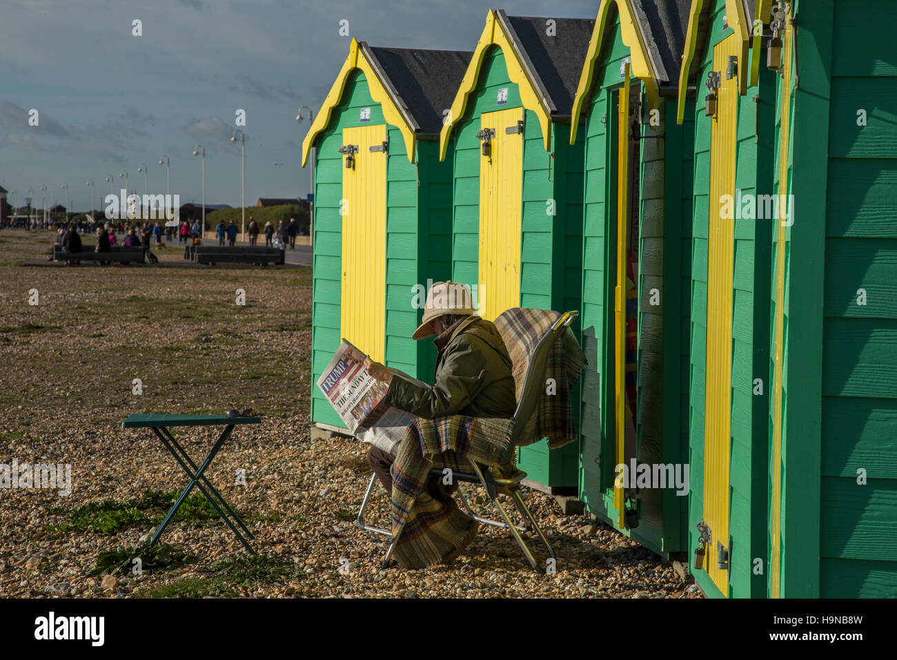 Donna, giornale di lettura al di fuori del beach hut, West Sussex Foto Stock