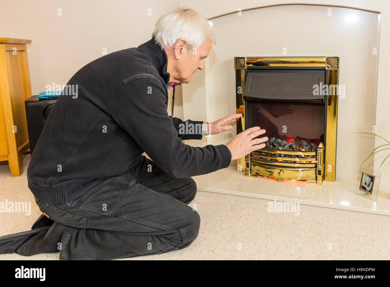 OAP cercando di mantenere caldo il riscaldamento le mani vicino al fuoco conservando le fatture verso il basso non può permettersi il riscaldamento bill elevata di gas le bollette di energia REGNO UNITO Inghilterra Foto Stock