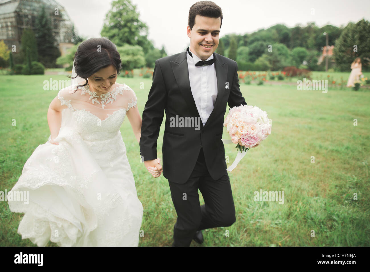 Sposi correre e saltare in park tenendo le mani Foto Stock