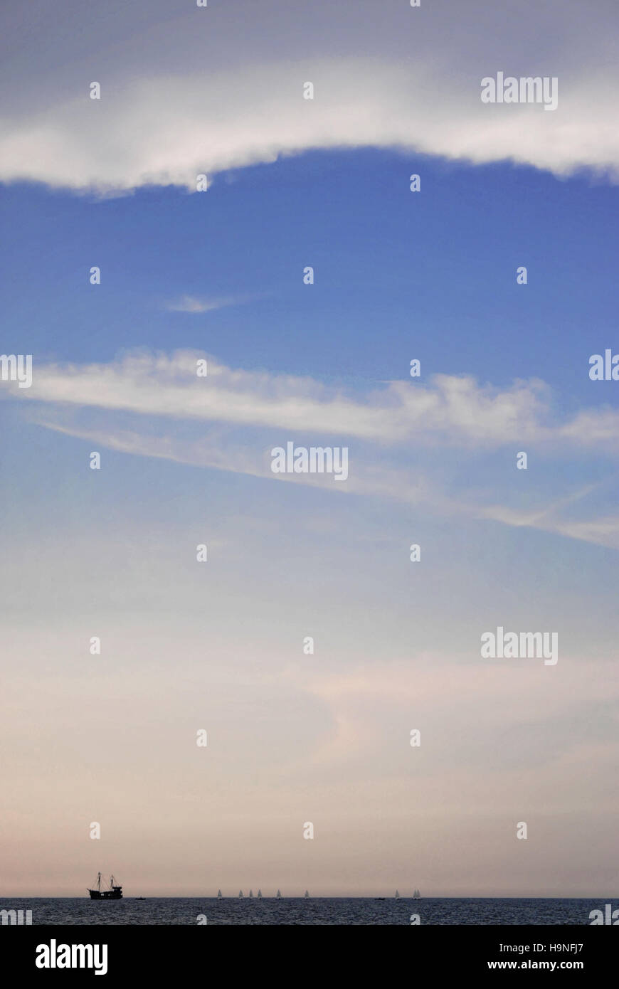 Un pesce in barca a vela l'orizzonte, seguita da poco le barche a vela Foto Stock