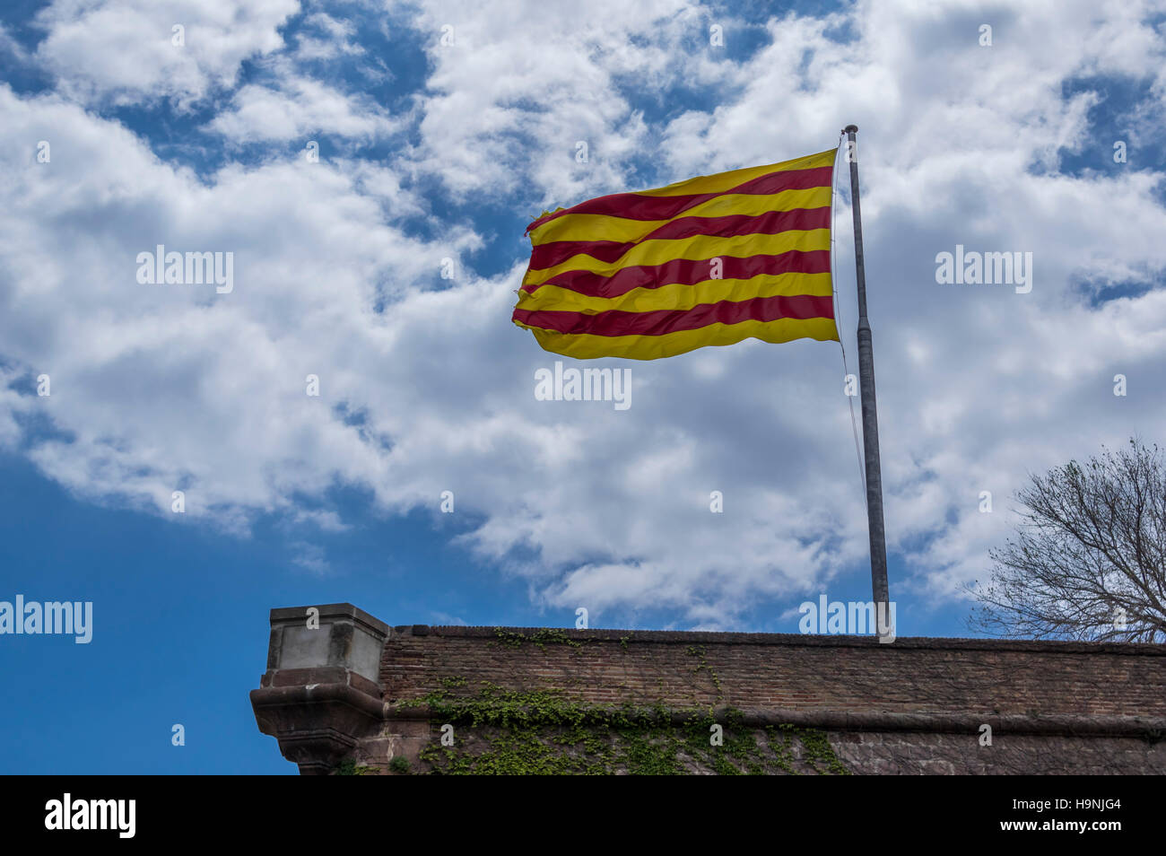 Usurati bandiera catalana contro il cielo blu e nuvole. Foto Stock