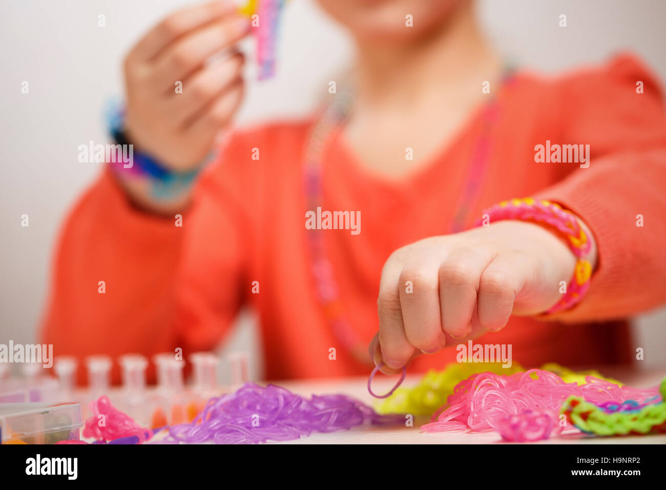 Ragazza di tessitura colorata banda di gomma bracciale, Foto Stock