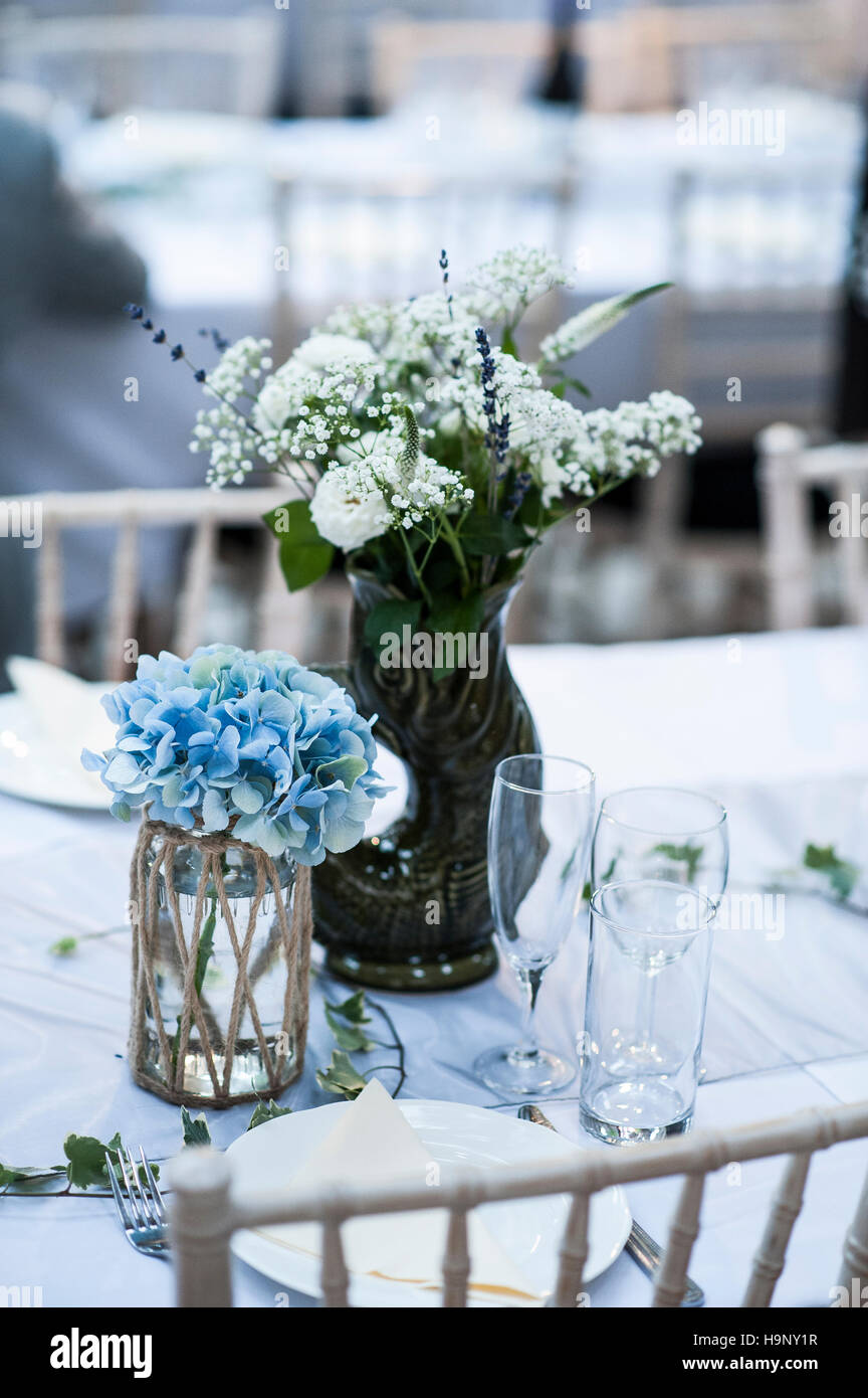 Un blu a tema Nozze set tavolo con fiori in un vaso. Foto Stock