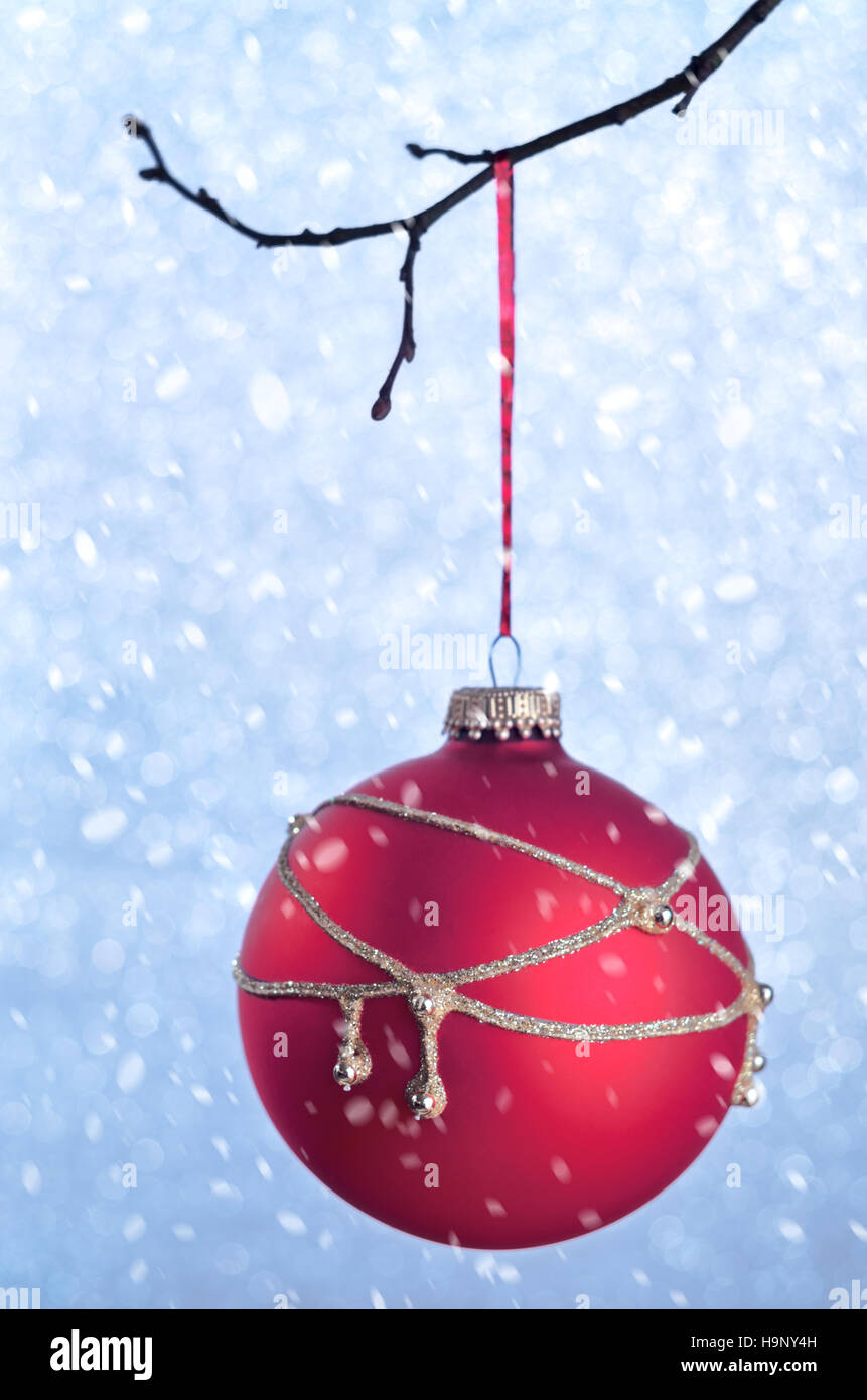 Rosso addobbi natalizi su blu sfocate vacanza brillante background concetto creativo con spazio per il testo sotto la neve. Le decorazioni di Natale sulle branche Foto Stock