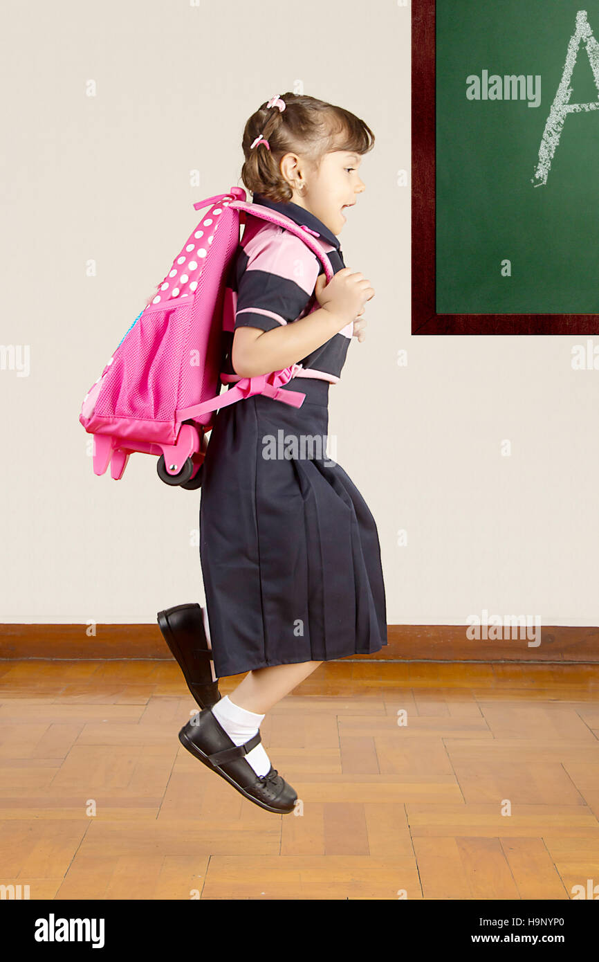 Piccolo felice School girl Jumping in aula scolastica Foto Stock