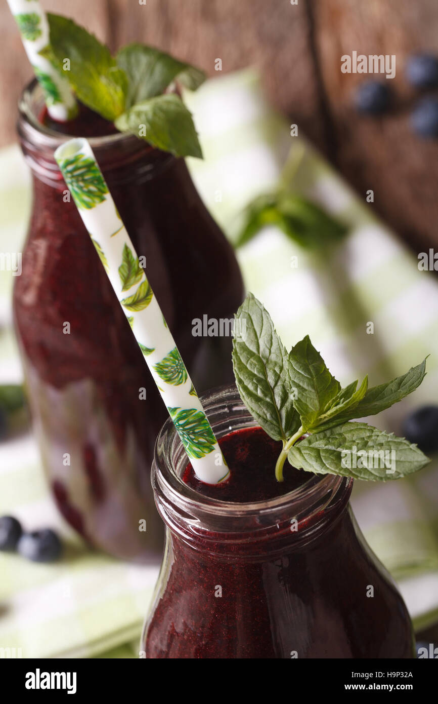 Ai mirtilli freschi succhi di frutta in una bottiglia di vetro macro verticale. Foto Stock
