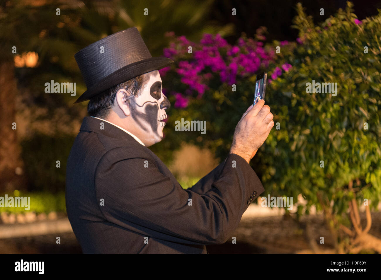 Un uomo vestito da dapper scheletro prende un telefono con fotocamera foto durante il giorno dei morti festival il 1 novembre 2016 in San Miguel De Allende, Guanajuato, Messico. La settimana di festa è un momento in cui i messicani benvenuti i morti alla messa a terra per una visita e celebrare la vita. Foto Stock