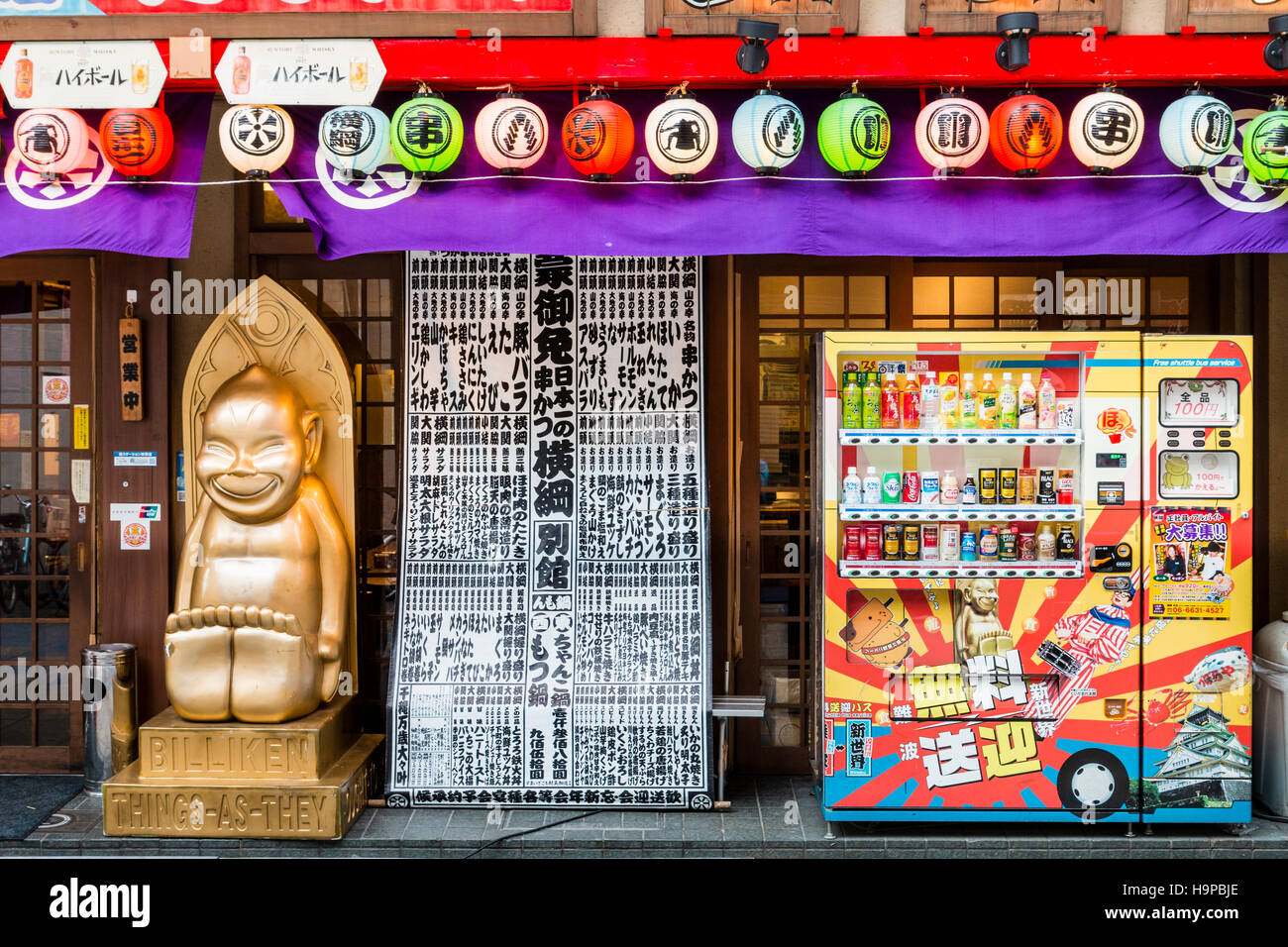 Giappone, Osaka, Shinsekai. Billiken popolare statua fuori del ristorante yokozuna, vendita Kushi-katsu, un famoso Osaka specialità alimentari. Distributore automatico. Foto Stock