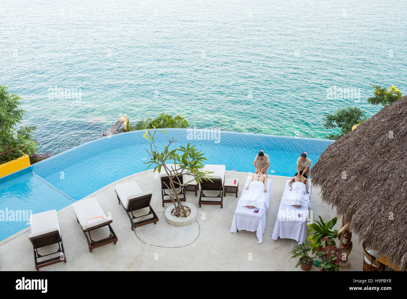 Vista da sopra a due donne di ottenere un massaggio sulla terrazza di un fronte oceano luxury wellness retreat Foto Stock