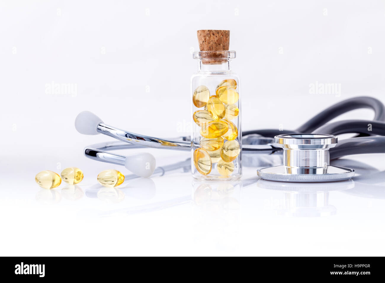 Olio di fegato di pesce di capsule in bottiglia con uno stetoscopio isolare su wh Foto Stock