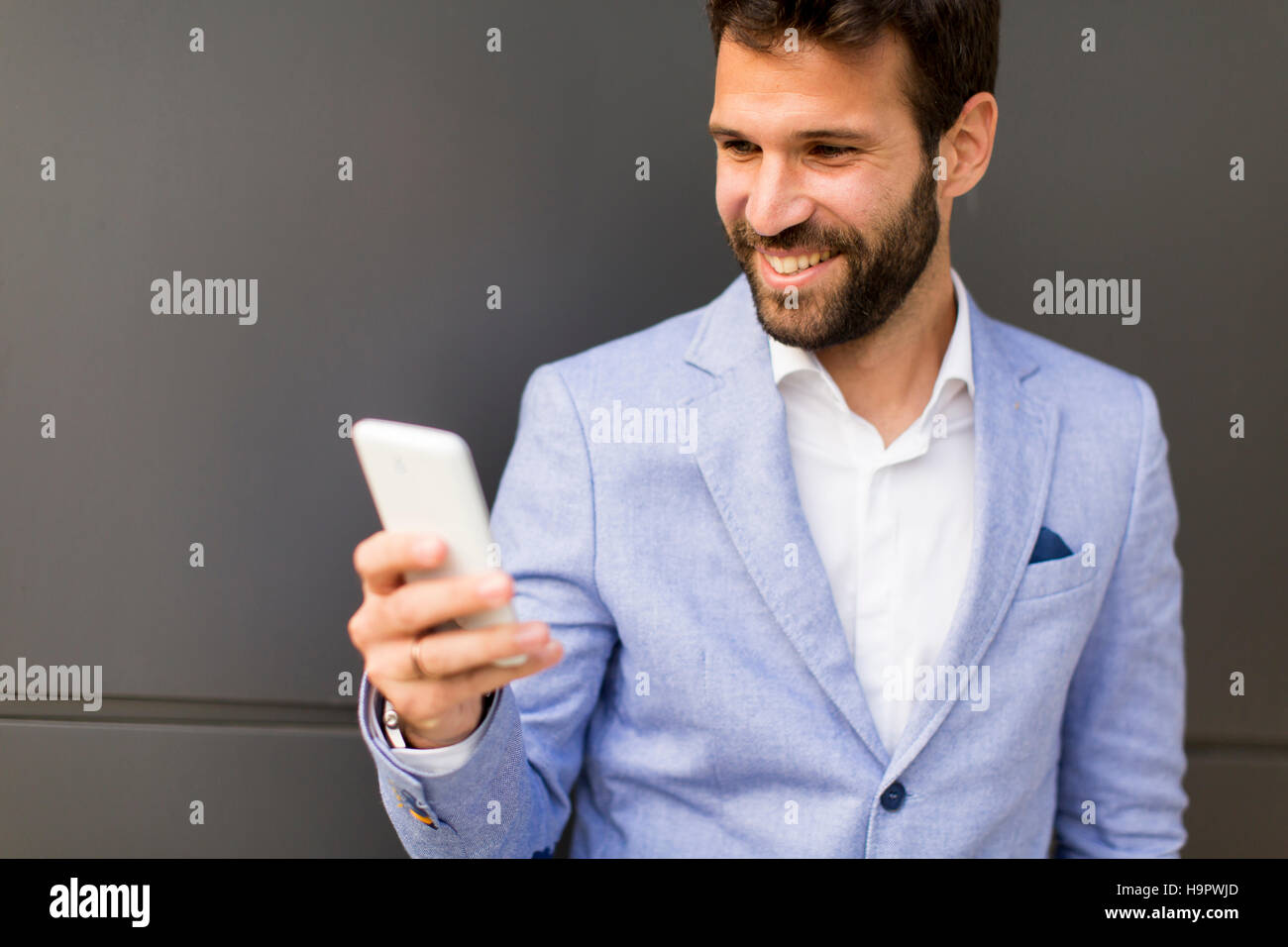 Imprenditore con un telefono dal muro nero Foto Stock