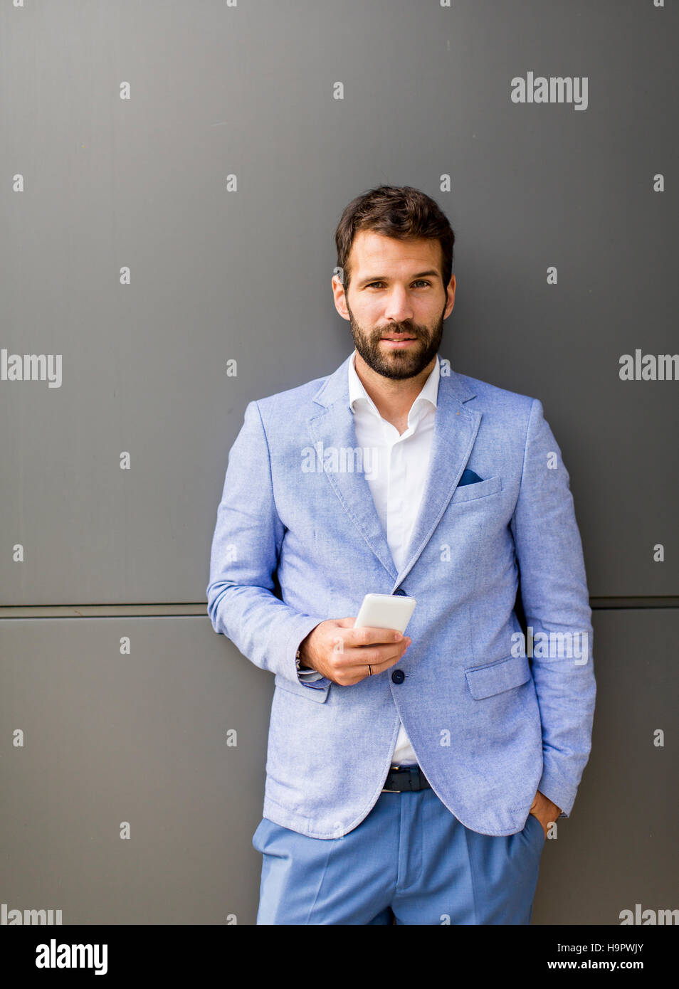 Imprenditore con un telefono dal muro nero Foto Stock