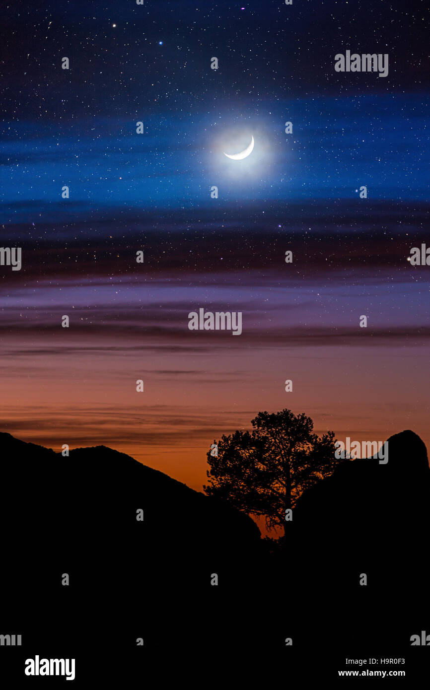 Silhouette di struttura tra le colline sotto il cielo notturno e luna Foto Stock