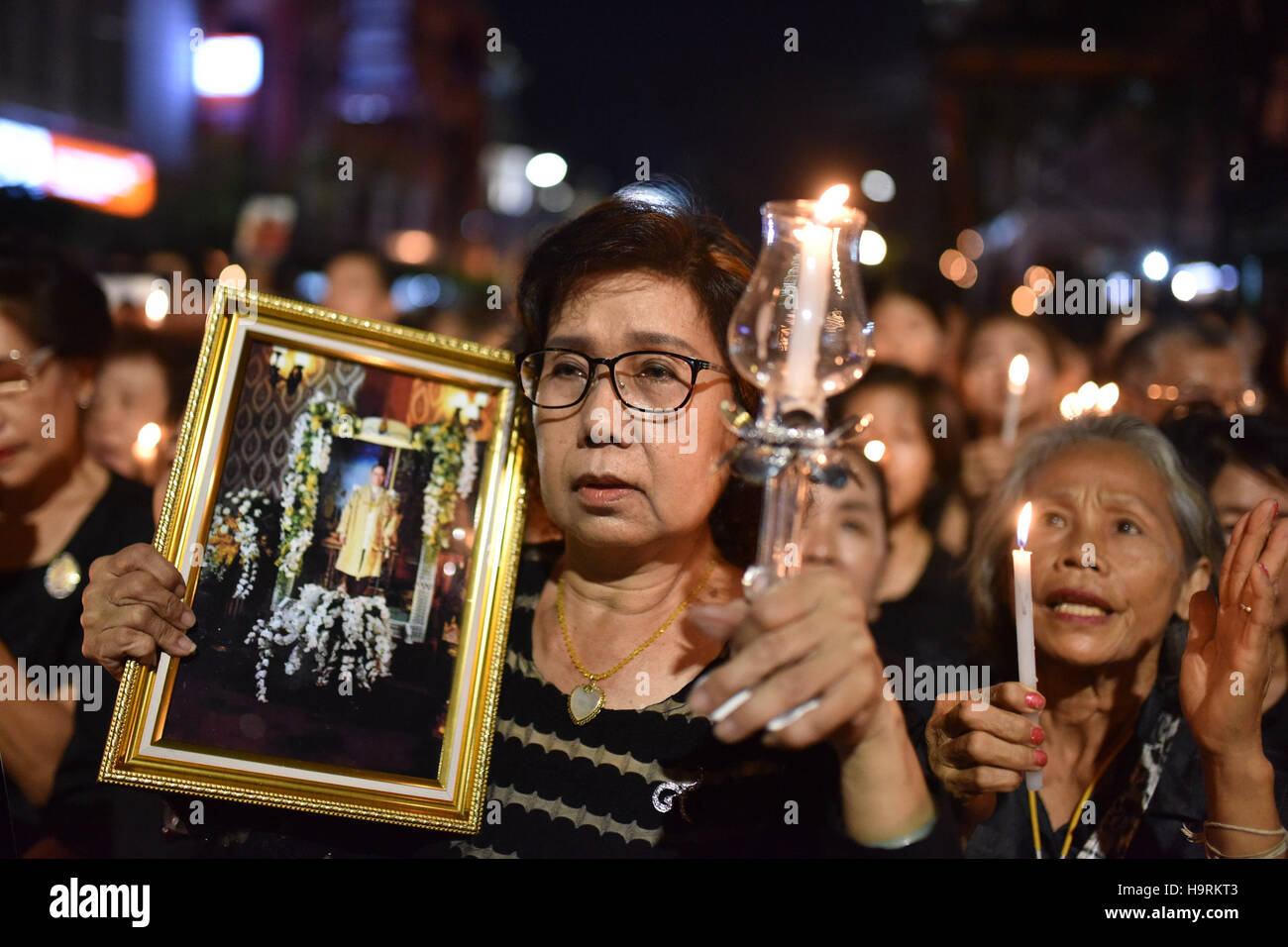 Bangkok, Tailandia. 26 Nov, 2016. Persone in lutto tenere le foto della Thailandia del compianto Re Bhumibol Adulyadej con illuminato candele durante un lutto manifestazione svoltasi presso la Chinatown di Bangkok, Thailandia, su nov. 26, 2016. La Thailandia è stato immerso nel dolore dopo il Re Bhumibol la morte su 13 Ottobre, con il lutto e riverenza di eventi che si tengono in tutto il paese durante un anno lungo periodo di lutto. Credito: Li Mangmang/Xinhua/Alamy Live News Foto Stock