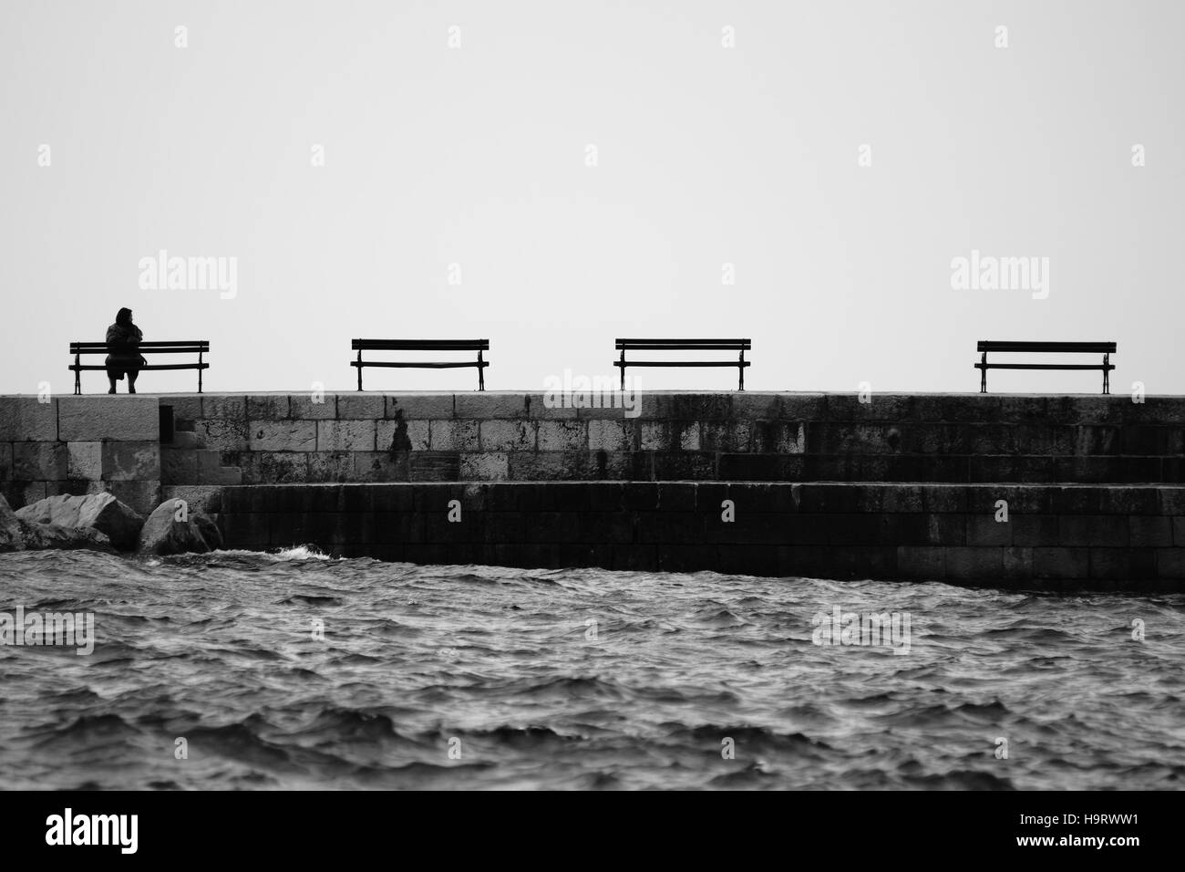 Donna seduta sul banco, da soli Foto Stock