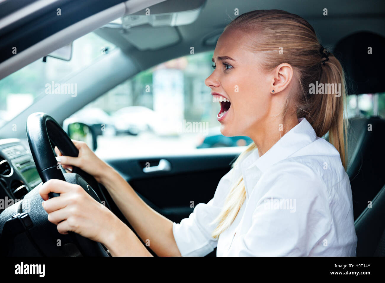 Spaventata business donna la guida la sua vettura e urlando Foto Stock