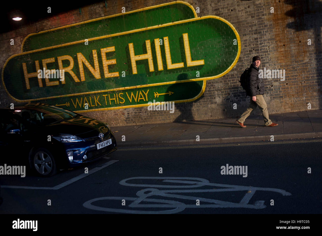 Una passeggiate a piedi sotto il segno di grandi dimensioni sotto il ponte della ferrovia annunciando Herne Hill, Lambeth SE24 nel sud di Londra. Foto Stock
