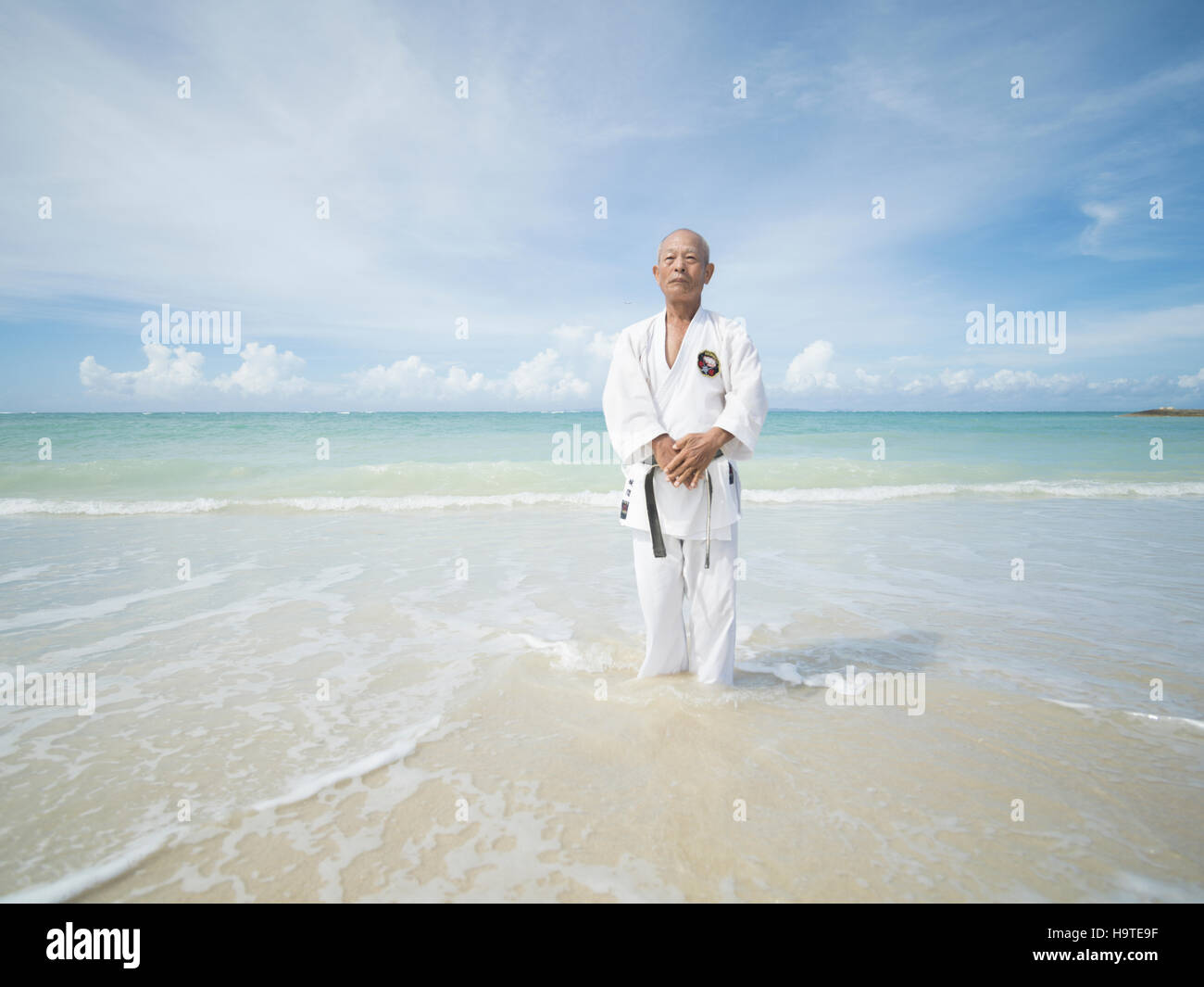 Anziani la cintura nera karate master formazione sulla spiaggia in Okinawa. Okinawa è uno dei la più lunga aspettativa di vita nel mondo Foto Stock