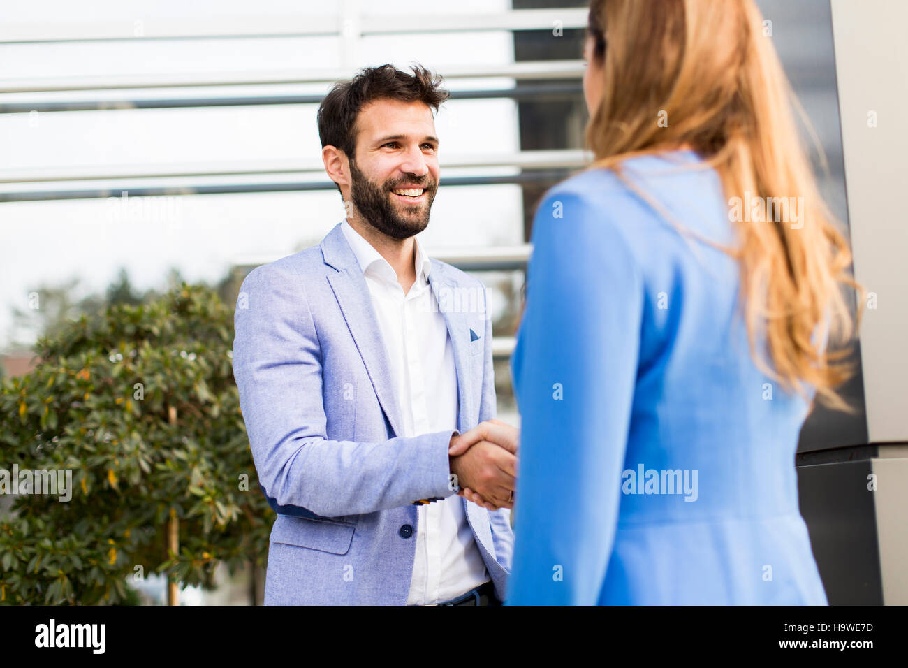 I giovani uomini di affari che agitano le mani di fronte all'edificio degli uffici Foto Stock