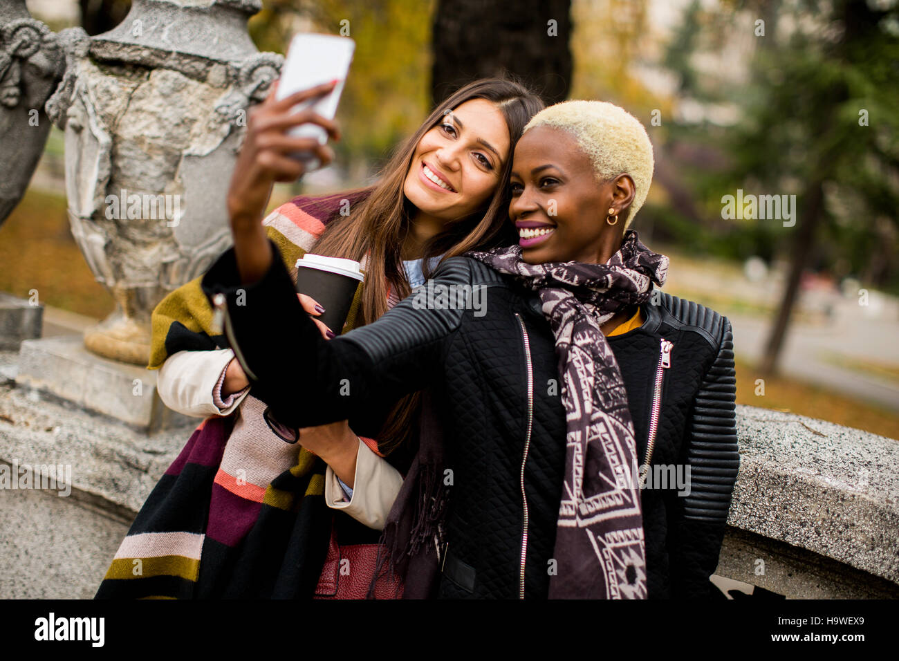 Giovane americano africano e caucasico donne tenendo selfie outdoor Foto Stock